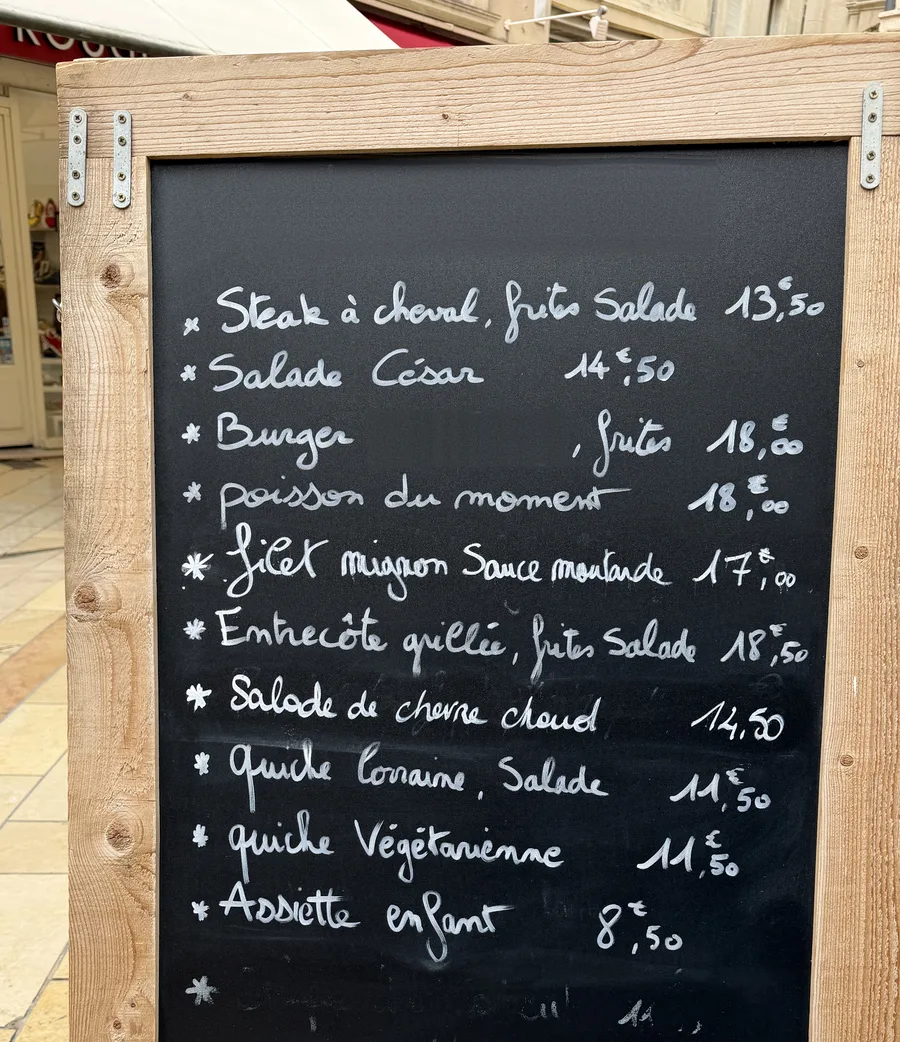 L'ardoise du jour d'un restaurant, écrite à la craie : dix plats et leurs prix